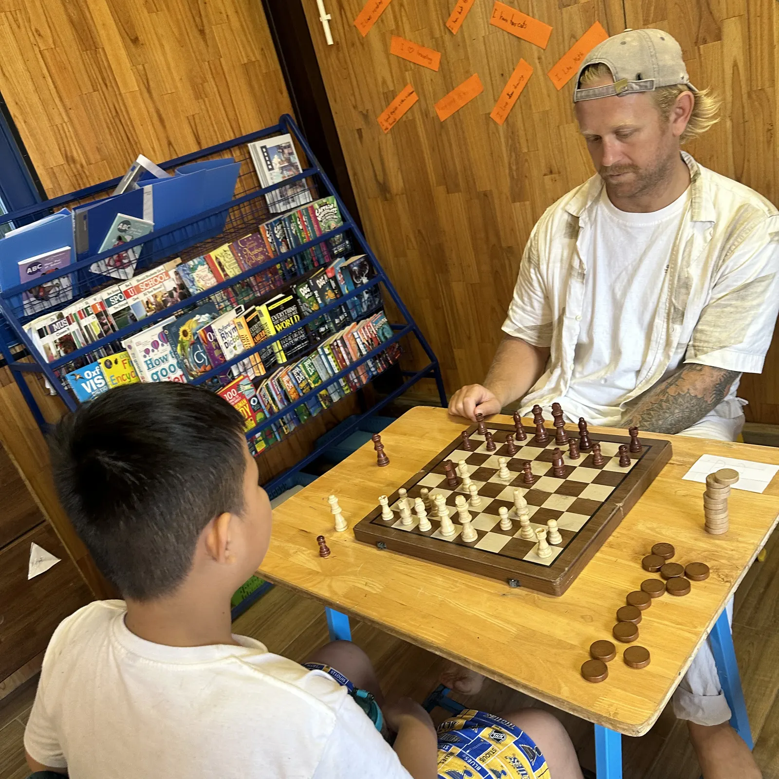 Mr. Caleb playing chess with a student in the library