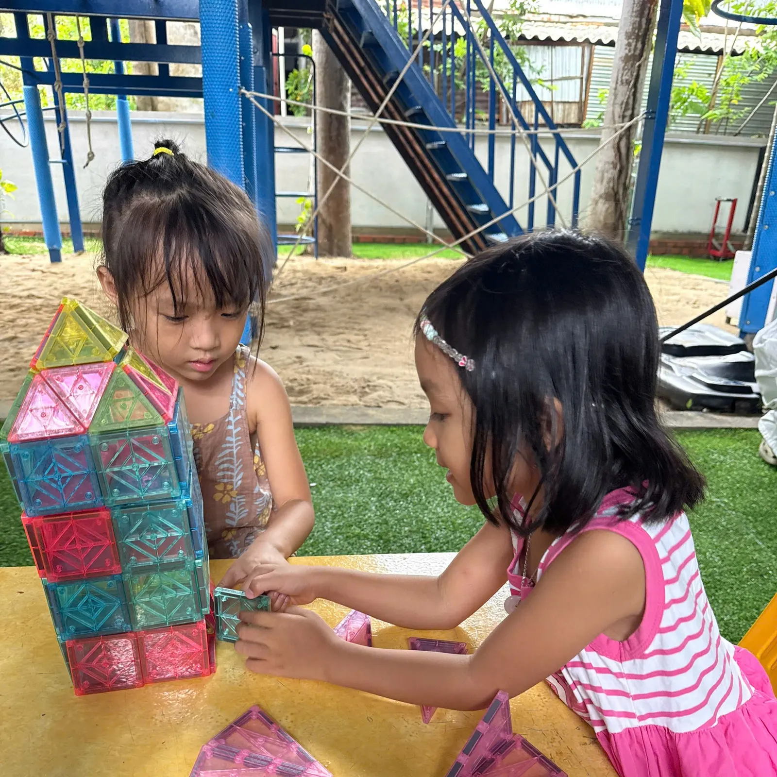 Year 1 students building with magnetic tiles outdoors
