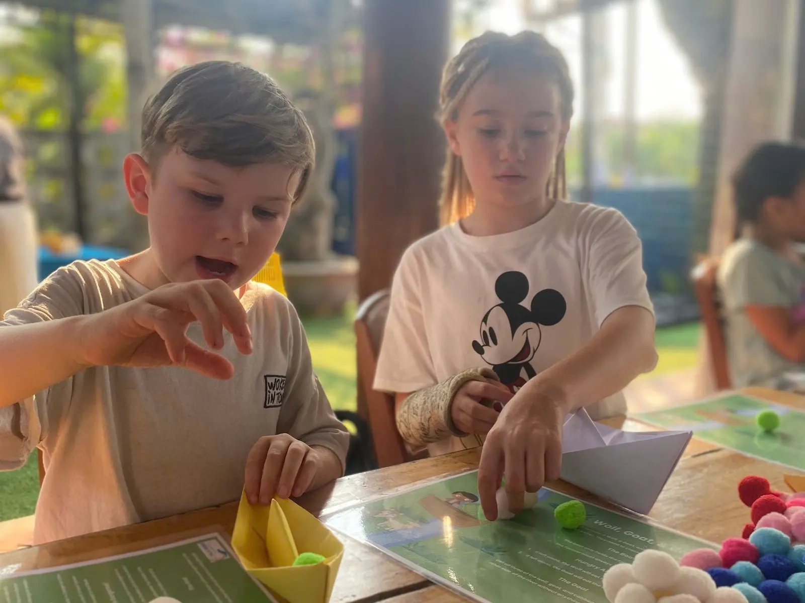 Students folding paper boats at a March Mathness game table
