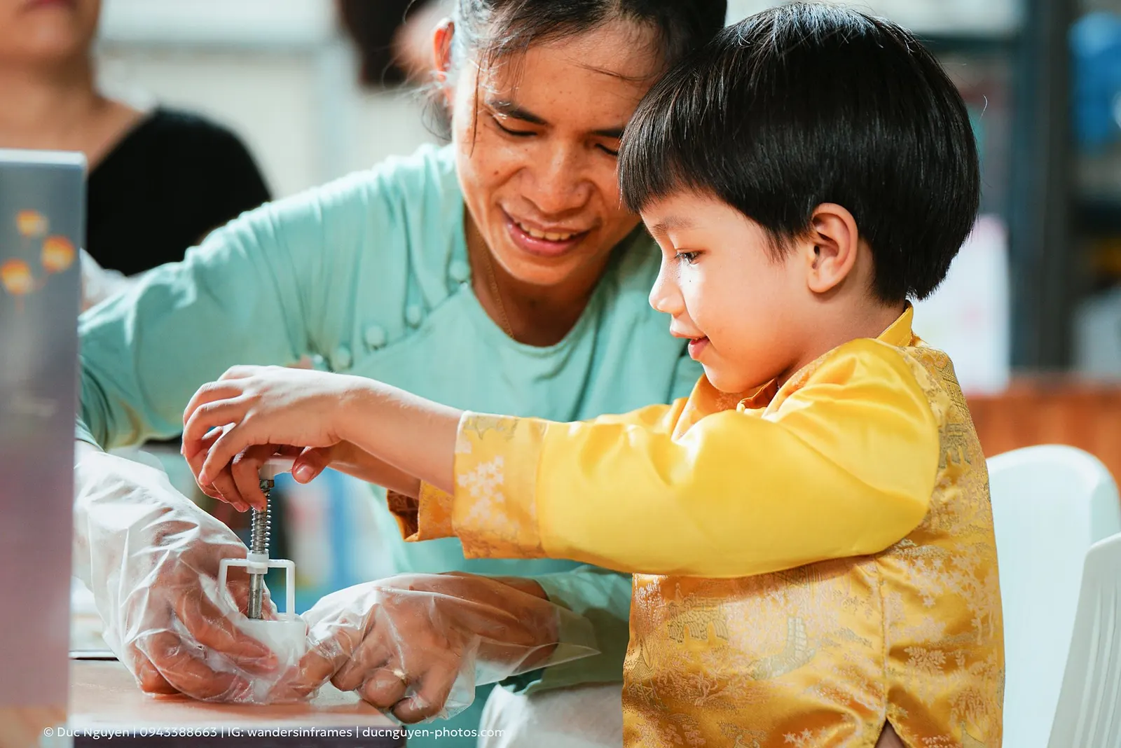 Ms. Thắm V pressing a mooncake mould with a child at the Mid-Autumn Festival