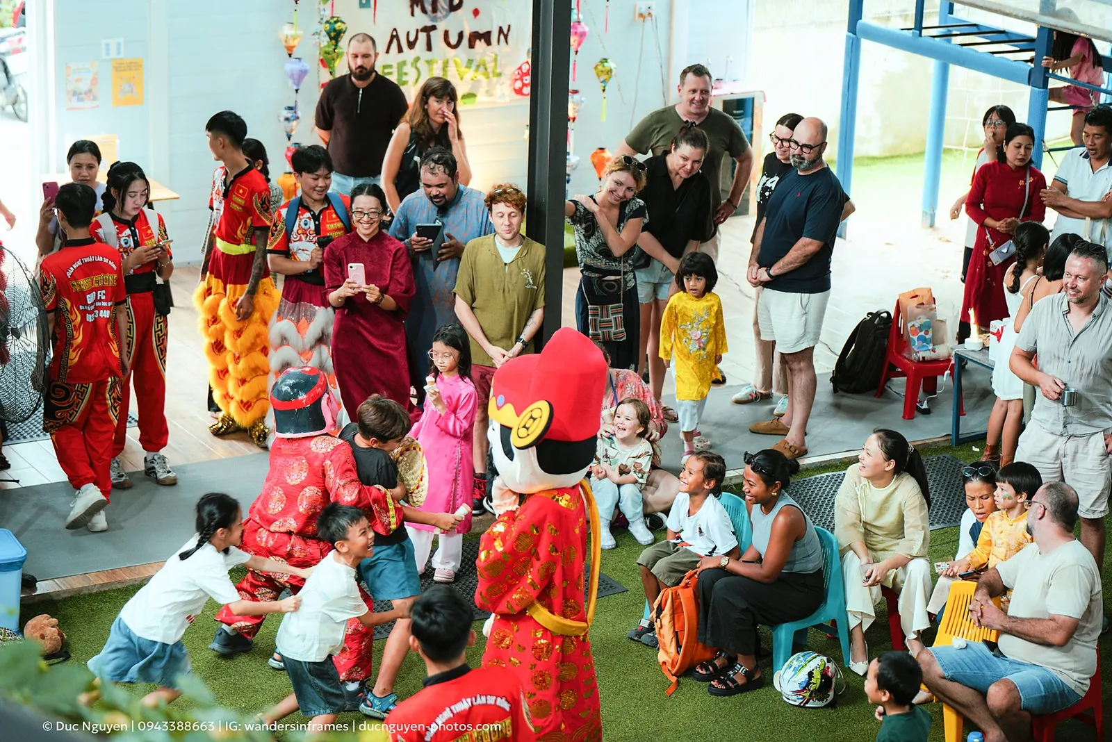 Children tugging at a masked performer as families watch at the Mid-Autumn Festival