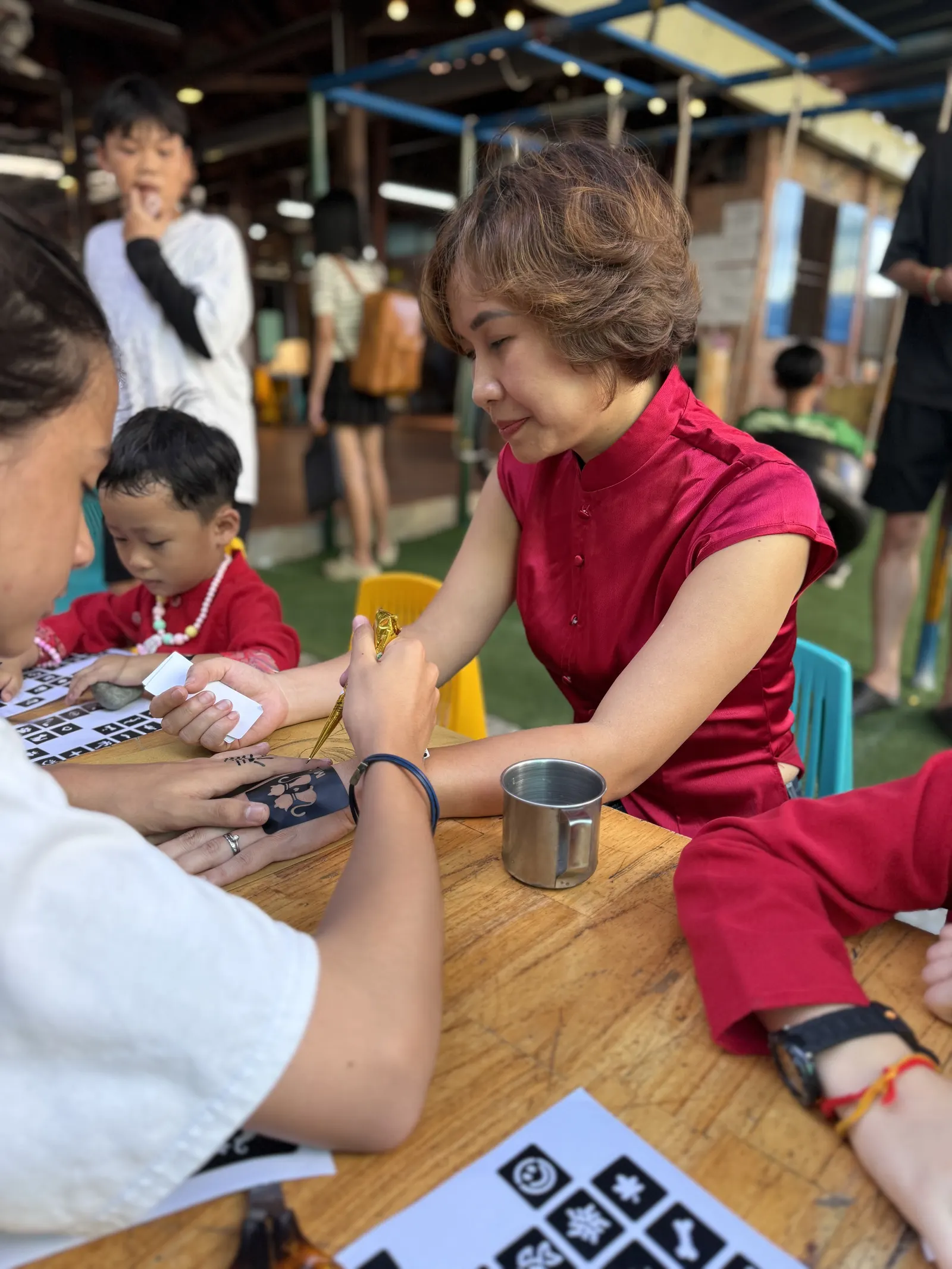 A student paints a henna design on Ms. Xuan's hand at the Mid-Autumn Festival