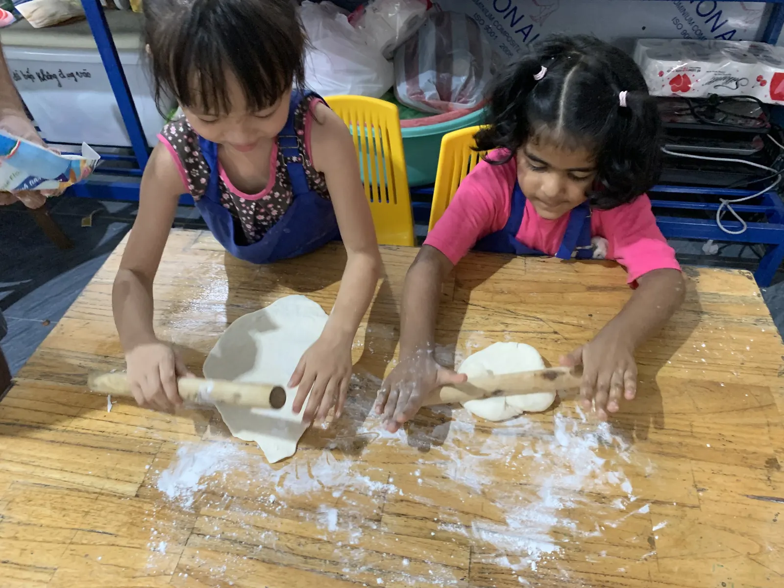 Primary students rolling dough on a floury table in cooking class