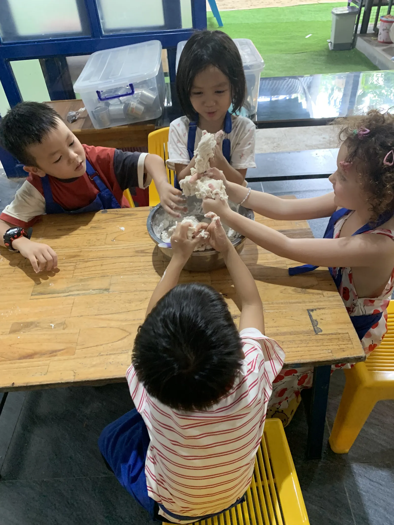 Primary students kneading dough together in cooking class