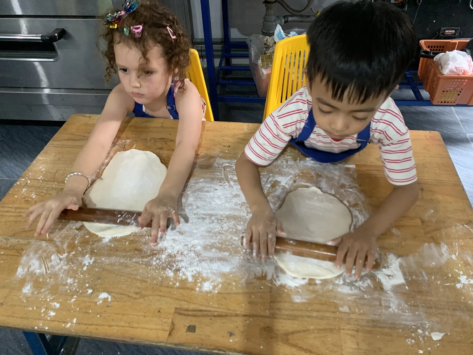 Two Primary students roll out their dough in cooking class