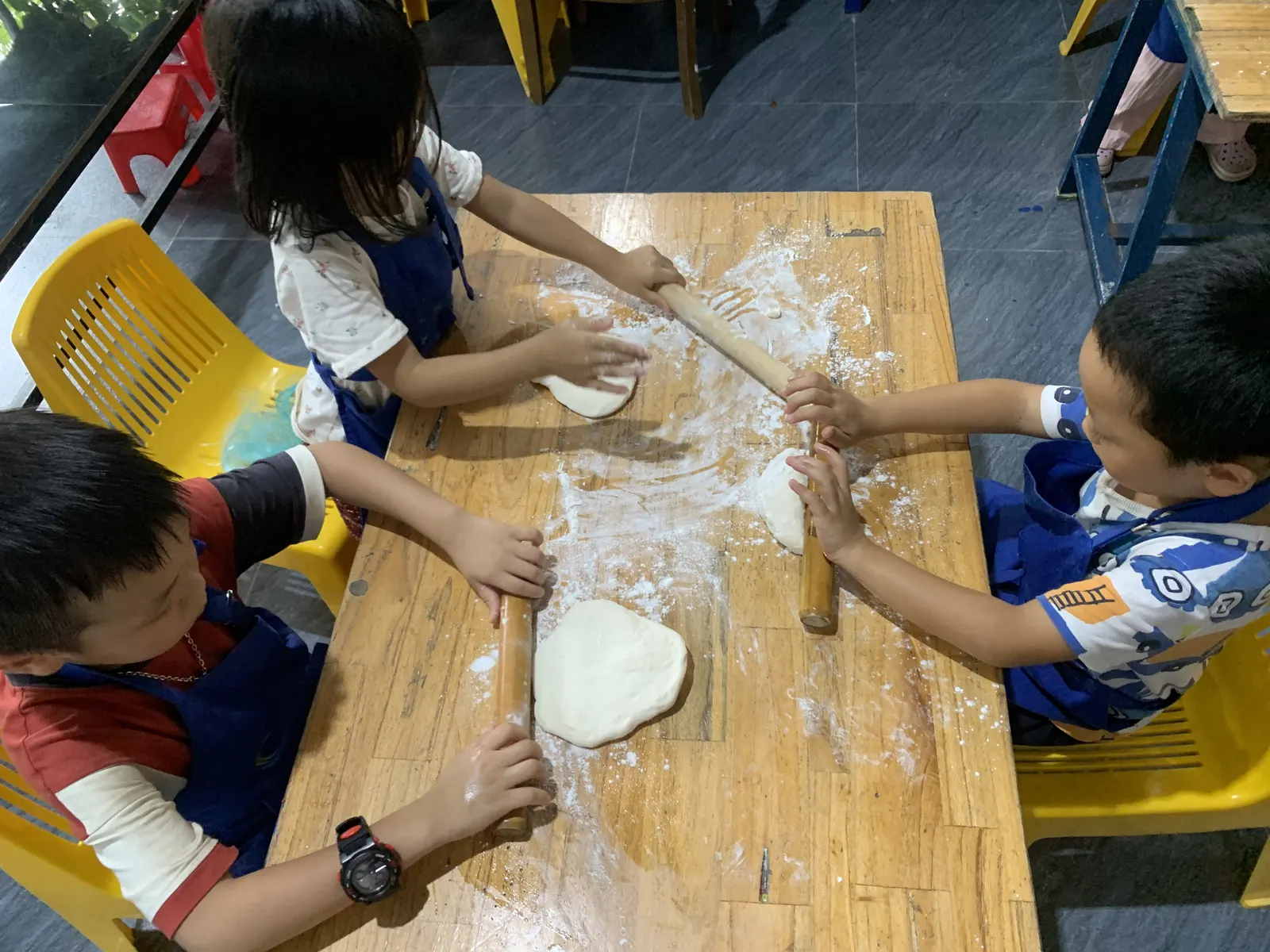 Primary students working the dough with rolling pins