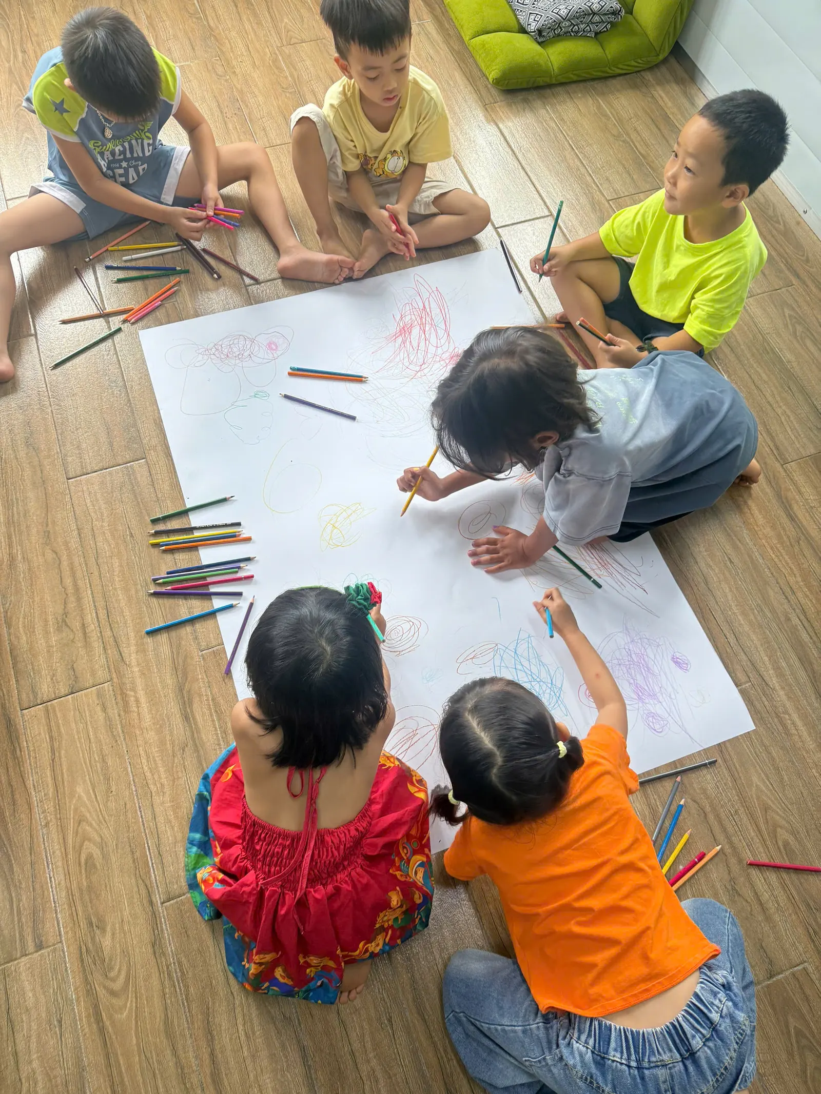 Primary students working on a drawing together on the classroom floor