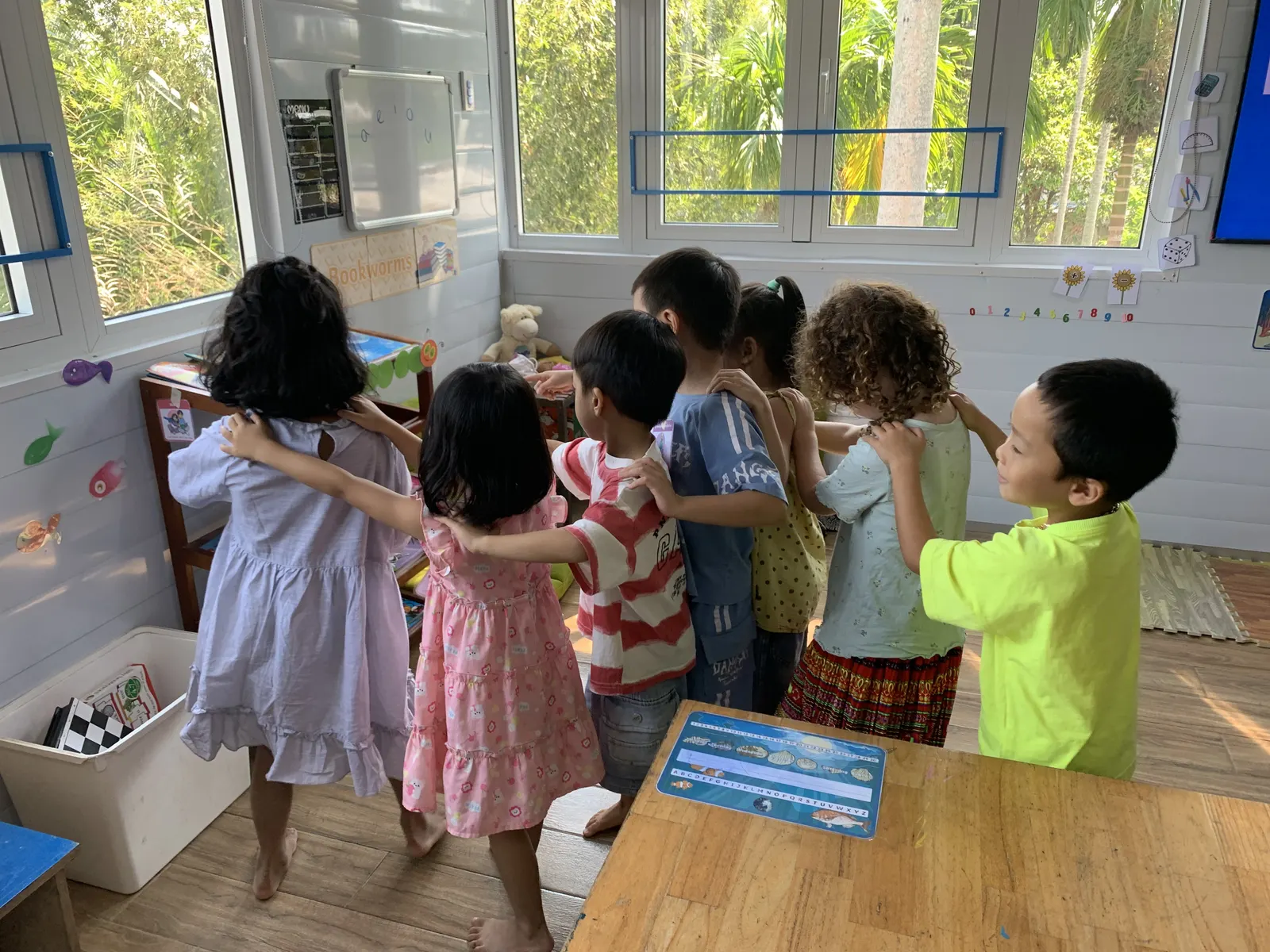 Primary students line up hand on shoulder for a classroom game