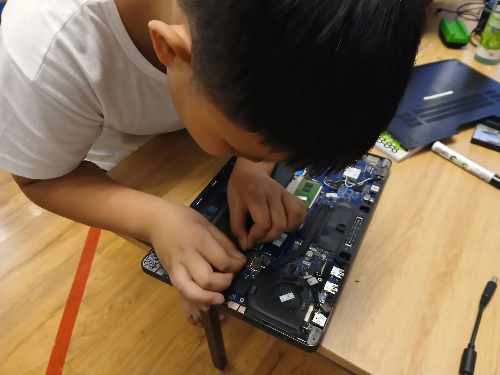 A Primary student taking a laptop apart to see how it works