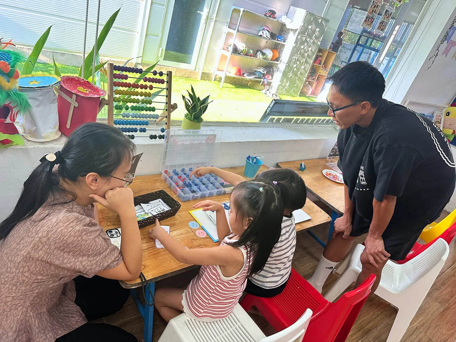 Một bé Early Years chọn thẻ chữ cái trong khi ba mẹ ngồi xem