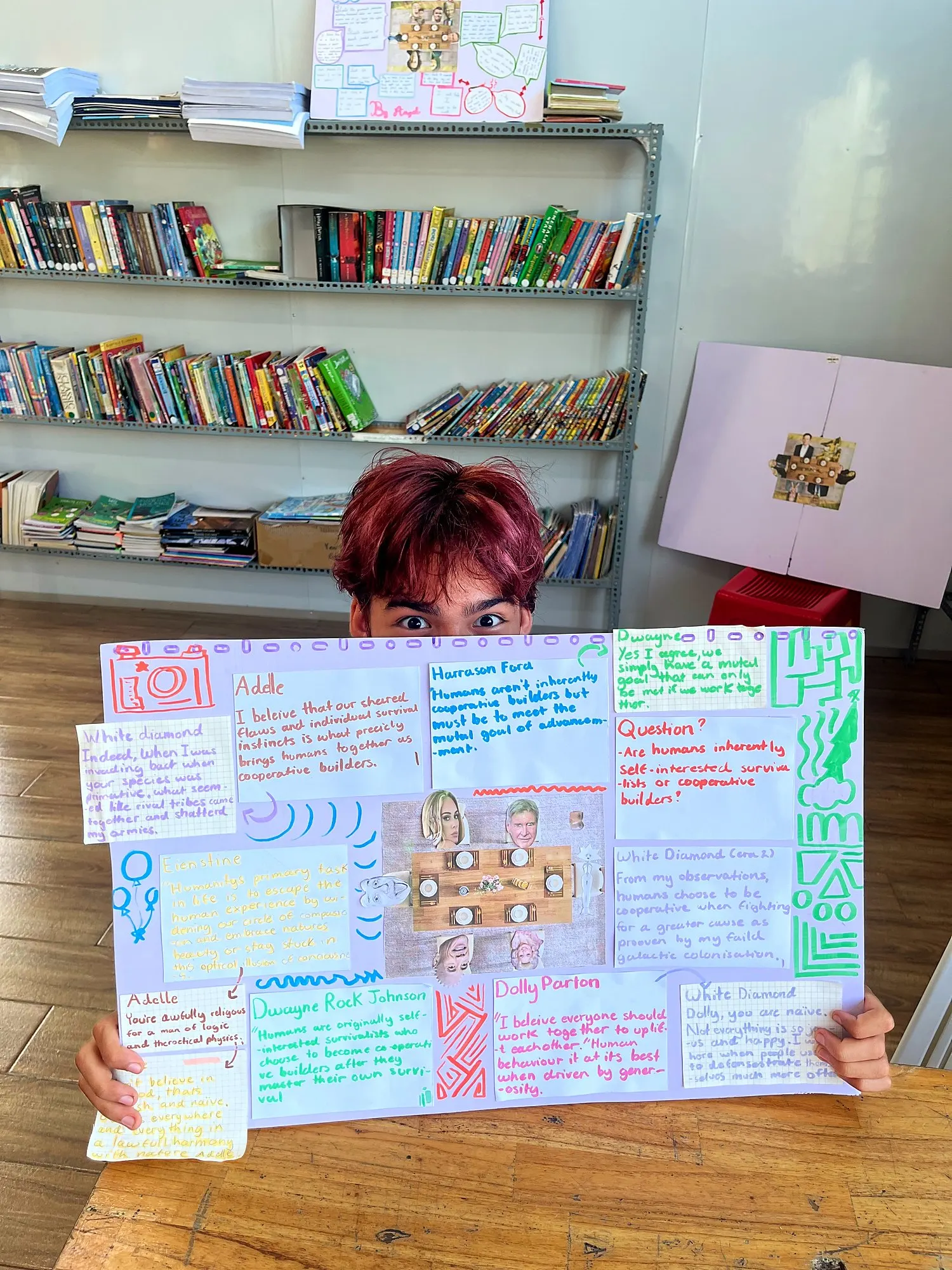 Một học viên Upper Secondary ló mắt sau poster tranh luận về việc con người có hợp tác với nhau hay không