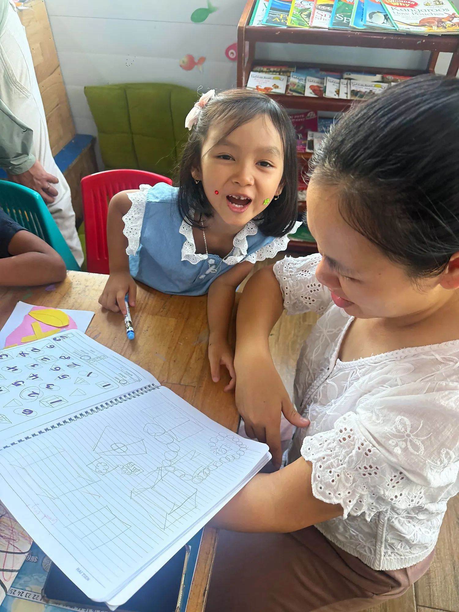 Một học viên Year 1 cho ba mẹ xem những hình vẽ trong vở Toán