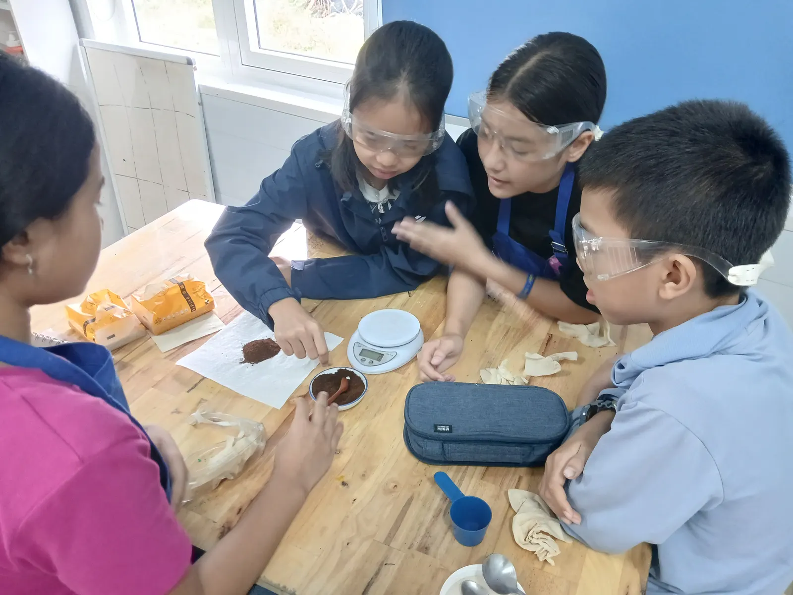 Lower Secondary students working through a practical together, all in goggles