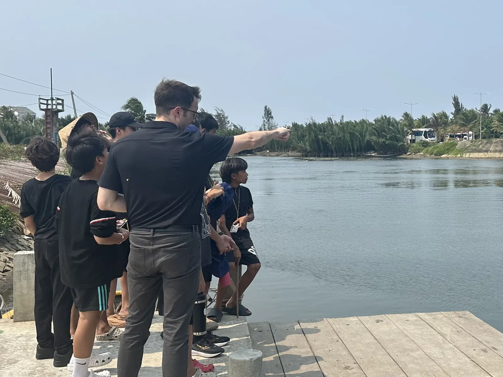 Mr. Bowen and Secondary students on a river jetty during a nature walk