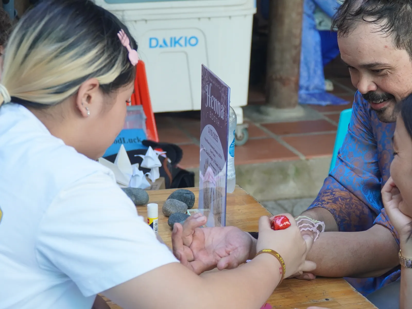A student painting henna on Mr. Seth's hand at the student-run Mid-Autumn Festival booth