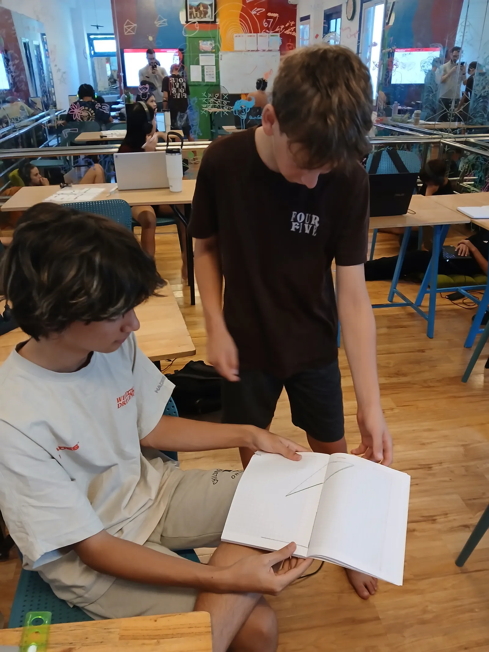 Two Upper Secondary students working a problem through together, the notebook open between them