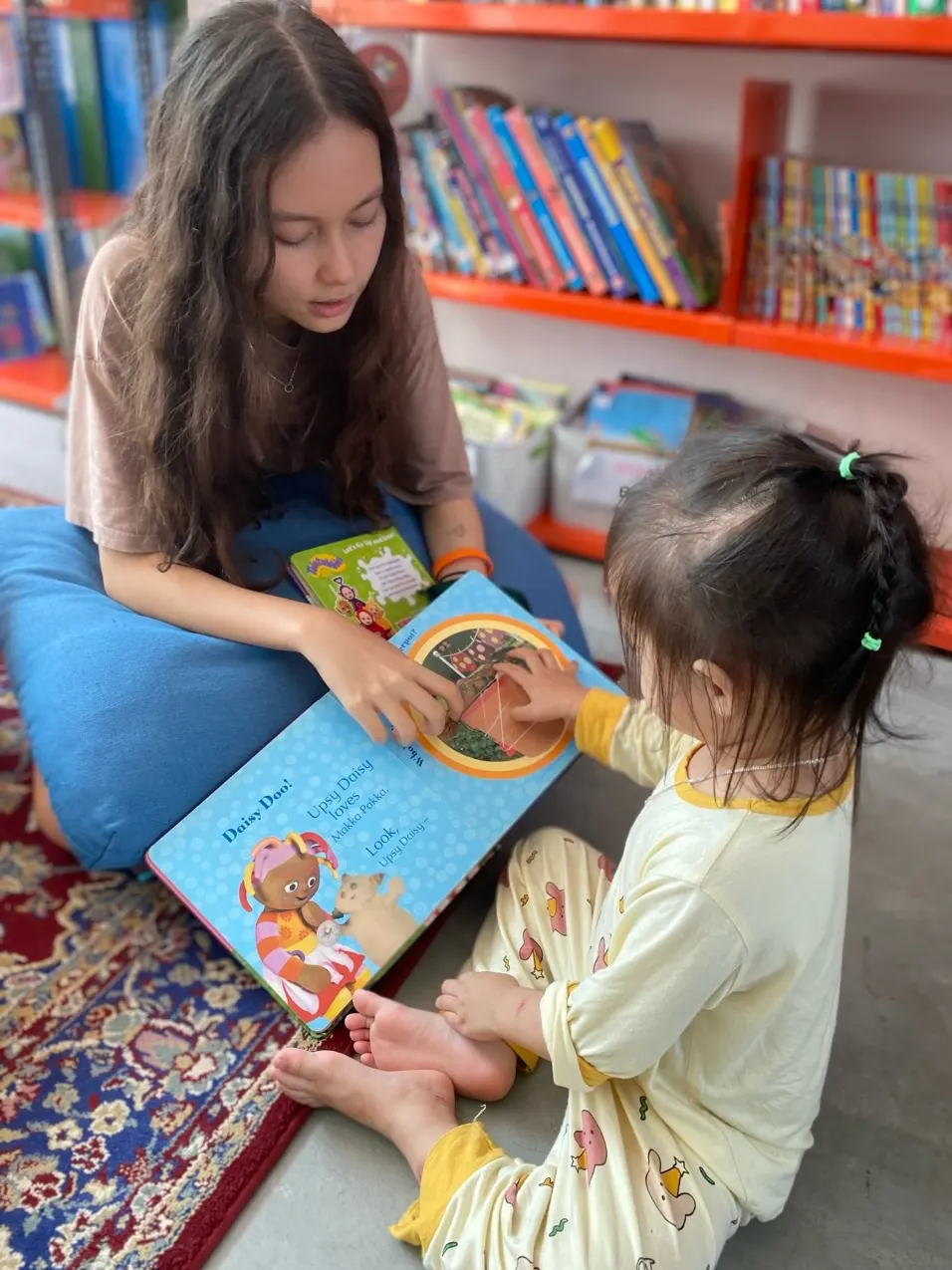 An Upper Secondary student reading a picture book with an Early Years child